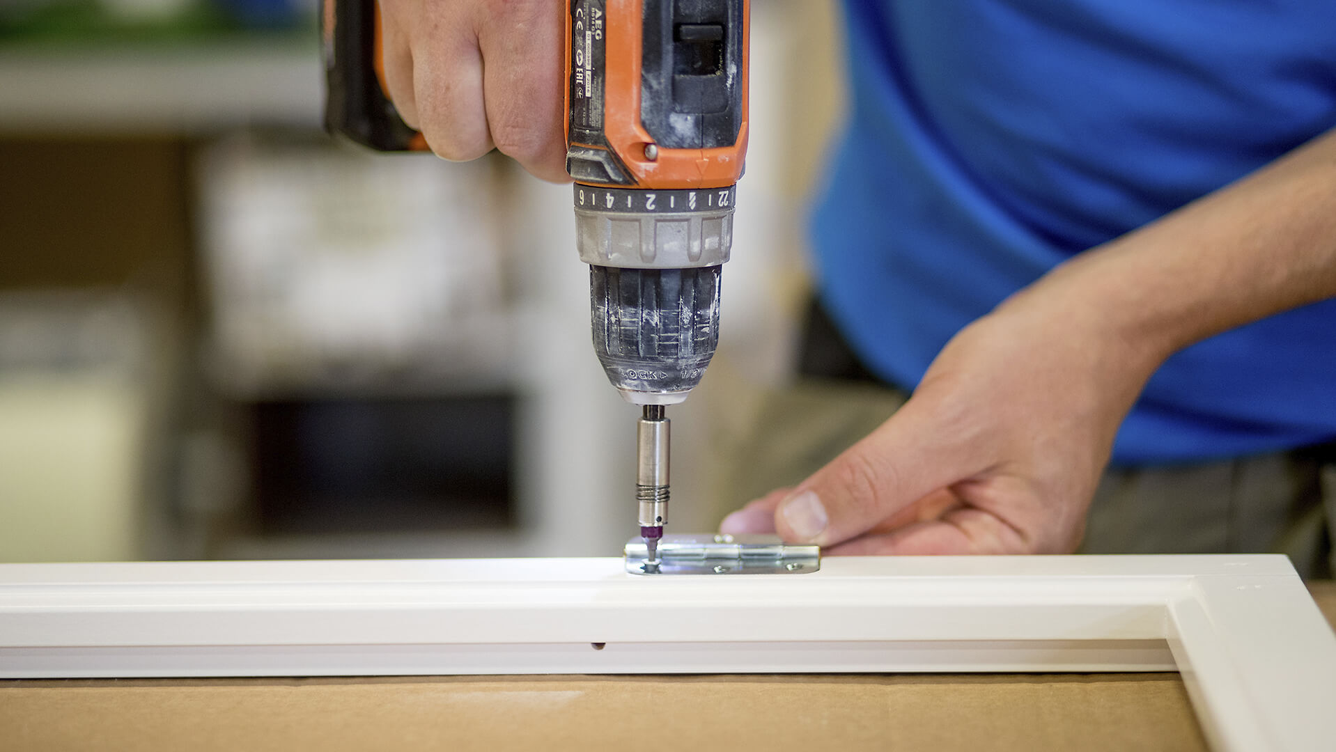 screws the hinge on a window sill