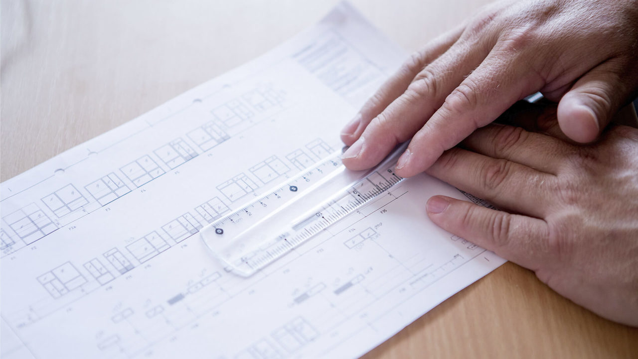 holding a ruler on a technical drawing of